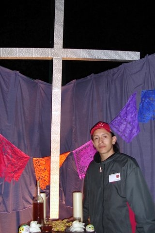 Isaac Montiel of New Haven stands beside a cross covered with the names of some of the thousands of people who died crossing the U.S.-Mexico border.