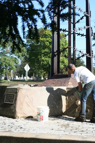 John Saunders of CS applyining cleaning agent to memorial.